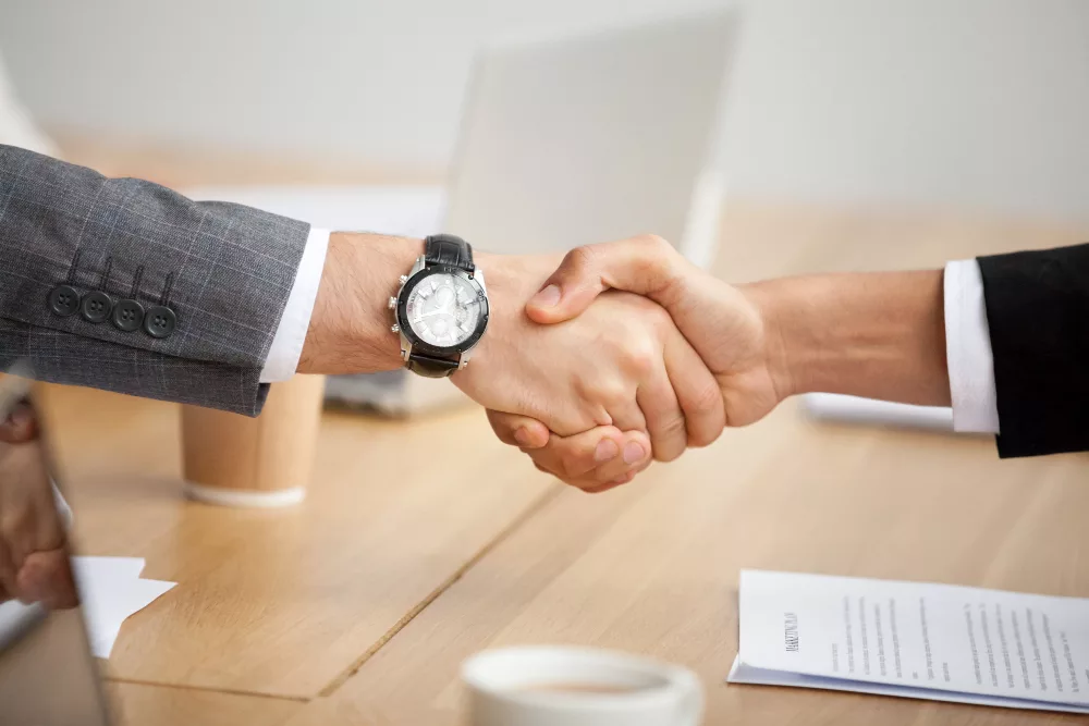 two businessmen in suits shaking hands for collaboration