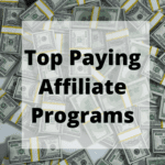 A large pile of U.S. dollar bills, both loose and in bundled stacks, serves as the background for bold black text that reads "Top Paying Affiliate Programs" within a semi-transparent white square.