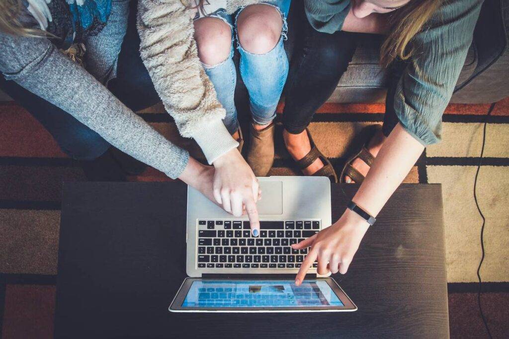 4 girls are pointing on the laptop screen