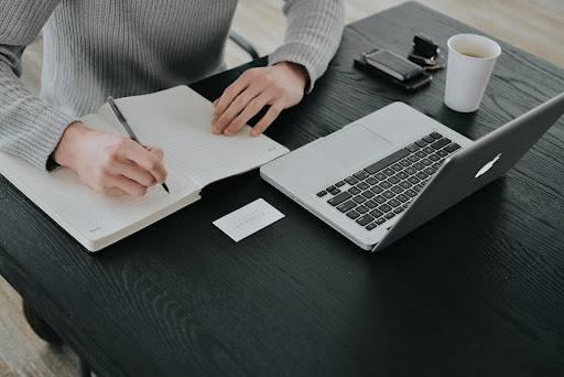 business man shit on chair and front of the apple MacBook and write on note diary with pen and image theme black color