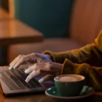 sideways woman working on her laptop in a coffee shop