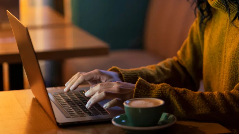 sideways woman working on her laptop in a coffee shop