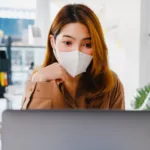 asia businesswoman wear face mask for social distancing in new normal situation for virus prevention while work office