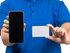 front view young female courier in blue uniform holding phone and white card
