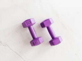 Purple all cast dumbbells on marble surface, increase-muscles