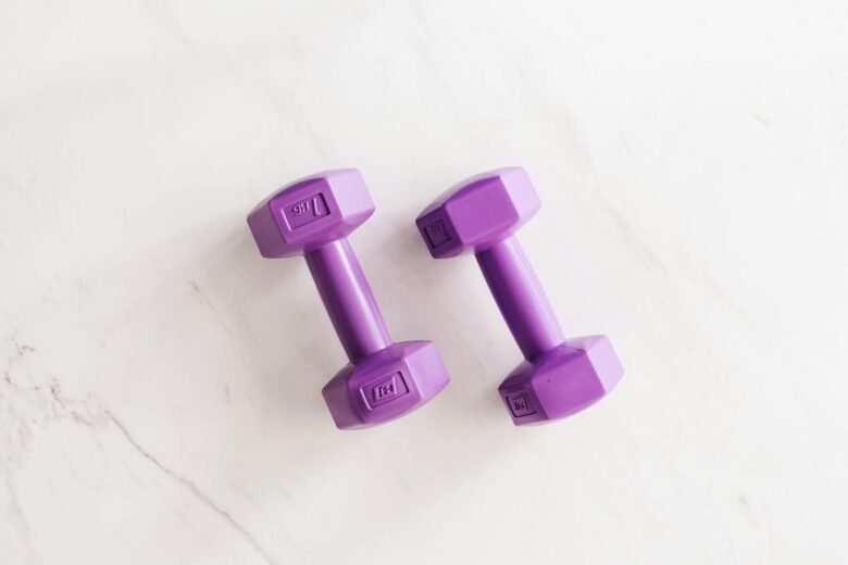 Purple all cast dumbbells on marble surface, increase-muscles