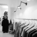 Stylish black and white interior of a boutique with clothes on racks, showcasing modern fashion.