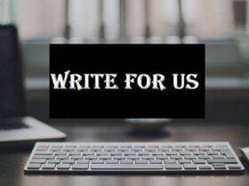 A sleek white keyboard is situated on a dark desk with a blurred background of a window and a computer screen. In the center of the image, a black rectangle with white text reads "WRITE FOR US" in bold, stylized font.