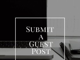 A laptop on a desk with notebooks and papers beside it. A white square frame overlay contains the text "Submit a Guest Post". The background is blurred, ensuring the text stands out prominently.