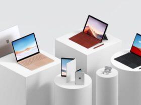 A collection of Microsoft Surface products displayed on white podiums against a gray background. The items include laptops, tablets with keyboards, earbuds, and a folding device. The products vary in colors including silver, bronze, and black.