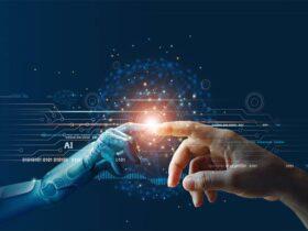 A human hand and a robotic hand reach out to touch fingertips against a dark background filled with digital circuitry and binary code. A glowing orb at their point of contact symbolizes connection or collaboration between humans and artificial intelligence.