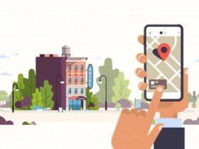 Illustration of someone using a smartphone with a map application, showing a location pin. The background features a small town with various buildings, trees, and street lamps. The person’s finger is pointing at the screen, indicating navigation.