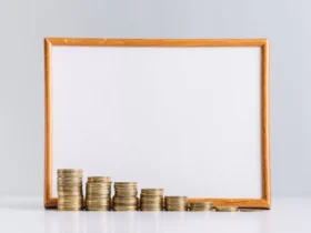 increasing stacked gold coins in front of blank white board on reflective desk