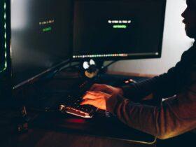 Crop hacker silhouette typing on computer keyboard while hacking system, New World Hacks & Cheats