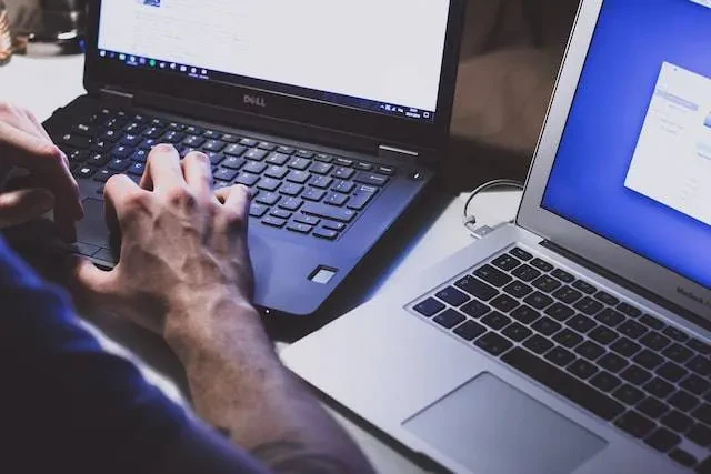 Person using two laptop