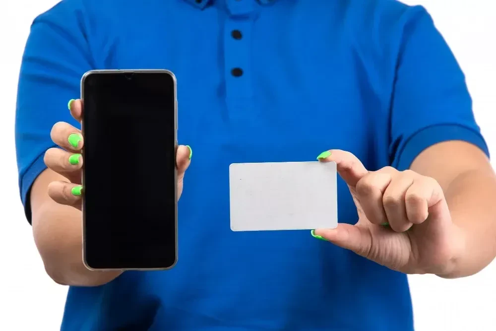 front view young female courier in blue uniform holding phone and white card