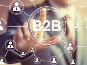 A person in a suit is pressing a virtual button labeled "B2B" on a transparent screen. The screen is filled with interconnected icons of people, symbolizing a business-to-business network. The background is blurred to highlight the interaction.