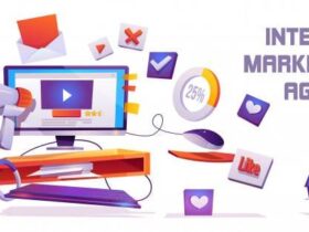 Illustration of a computer desk with a monitor displaying a play button, surrounded by digital marketing symbols such as a megaphone, percentage chart, thumbs-up, and notification icons. Text on the right reads "Internet Marketing Agency.