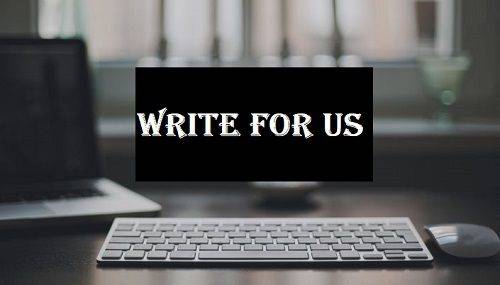 A sleek white keyboard is situated on a dark desk with a blurred background of a window and a computer screen. In the center of the image, a black rectangle with white text reads "WRITE FOR US" in bold, stylized font.