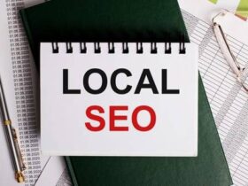 A notepad with "LOCAL SEO" written on it is placed on top of several documents with numbers. A pair of glasses and a pen are nearby.