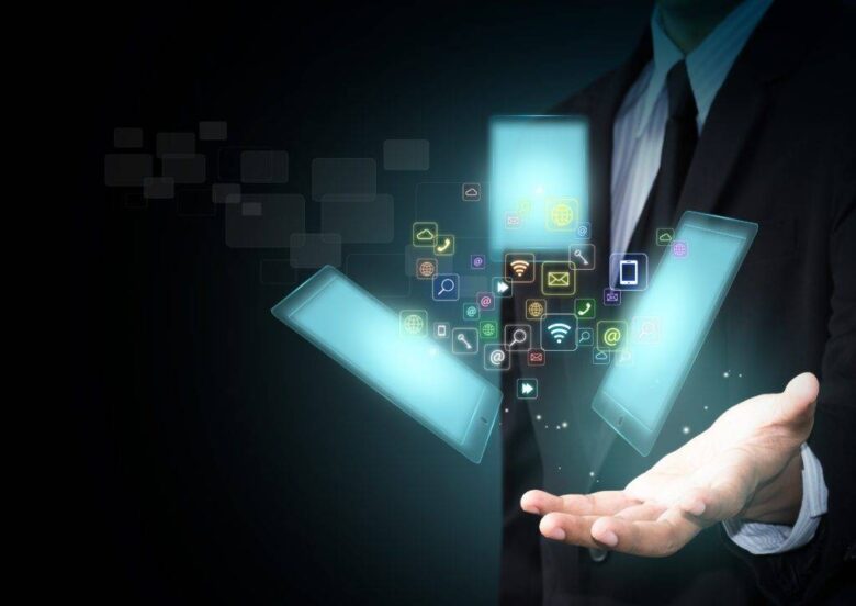 A person in a suit holds a glowing digital hologram displaying various app icons and symbols, with three transparent rectangles hovering above their hand.