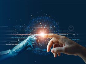 A human hand and a robotic hand reach out to touch fingertips against a dark background filled with digital circuitry and binary code. A glowing orb at their point of contact symbolizes connection or collaboration between humans and artificial intelligence.