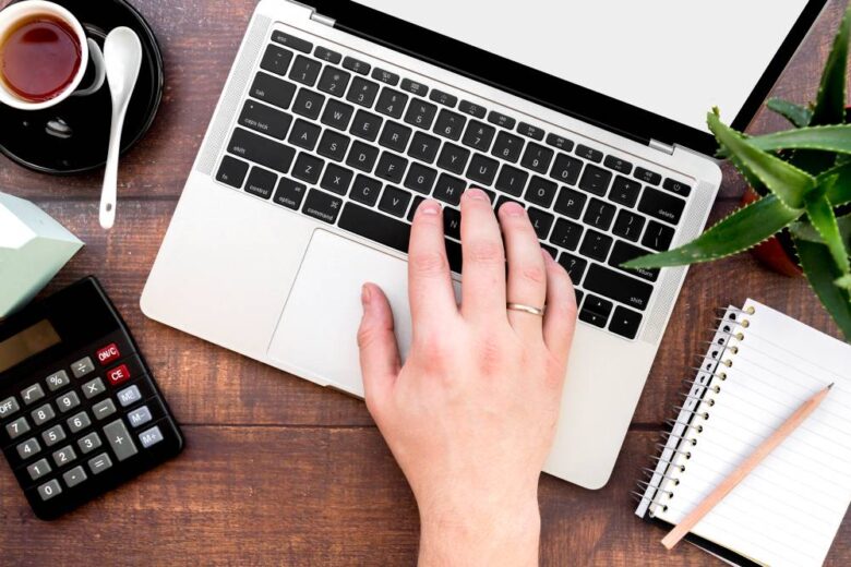 person's hand typing on laptop