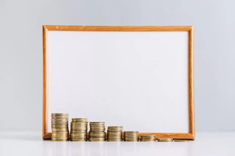 increasing stacked gold coins in front of blank white board on reflective desk