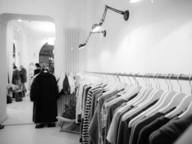Stylish black and white interior of a boutique with clothes on racks, showcasing modern fashion.